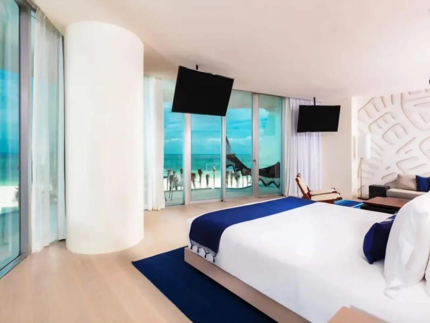 Premier Suite king bed beside balcony doors and ocean views at SLS Cancun.