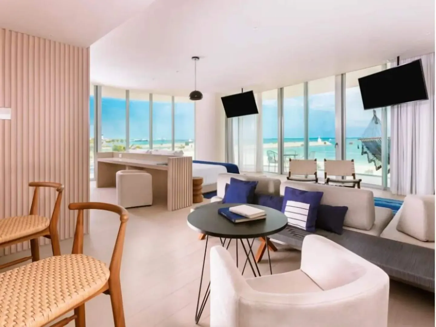 Premier Suite lounge, dining chairs, king bed, and oceanfront windows at SLS Cancun.