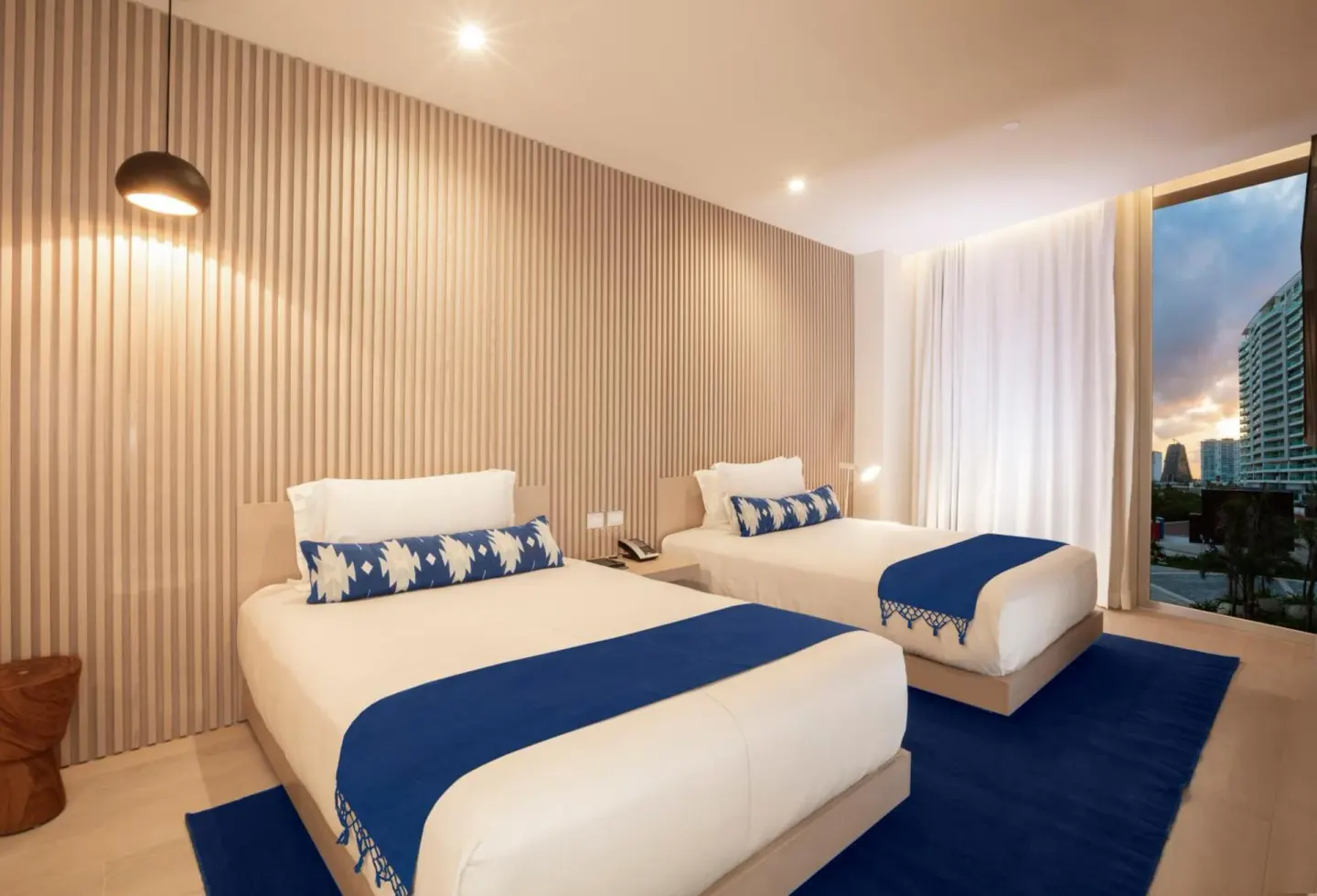 Superior Street View room with two beds, blue rugs, and city-facing window at SLS Cancun.