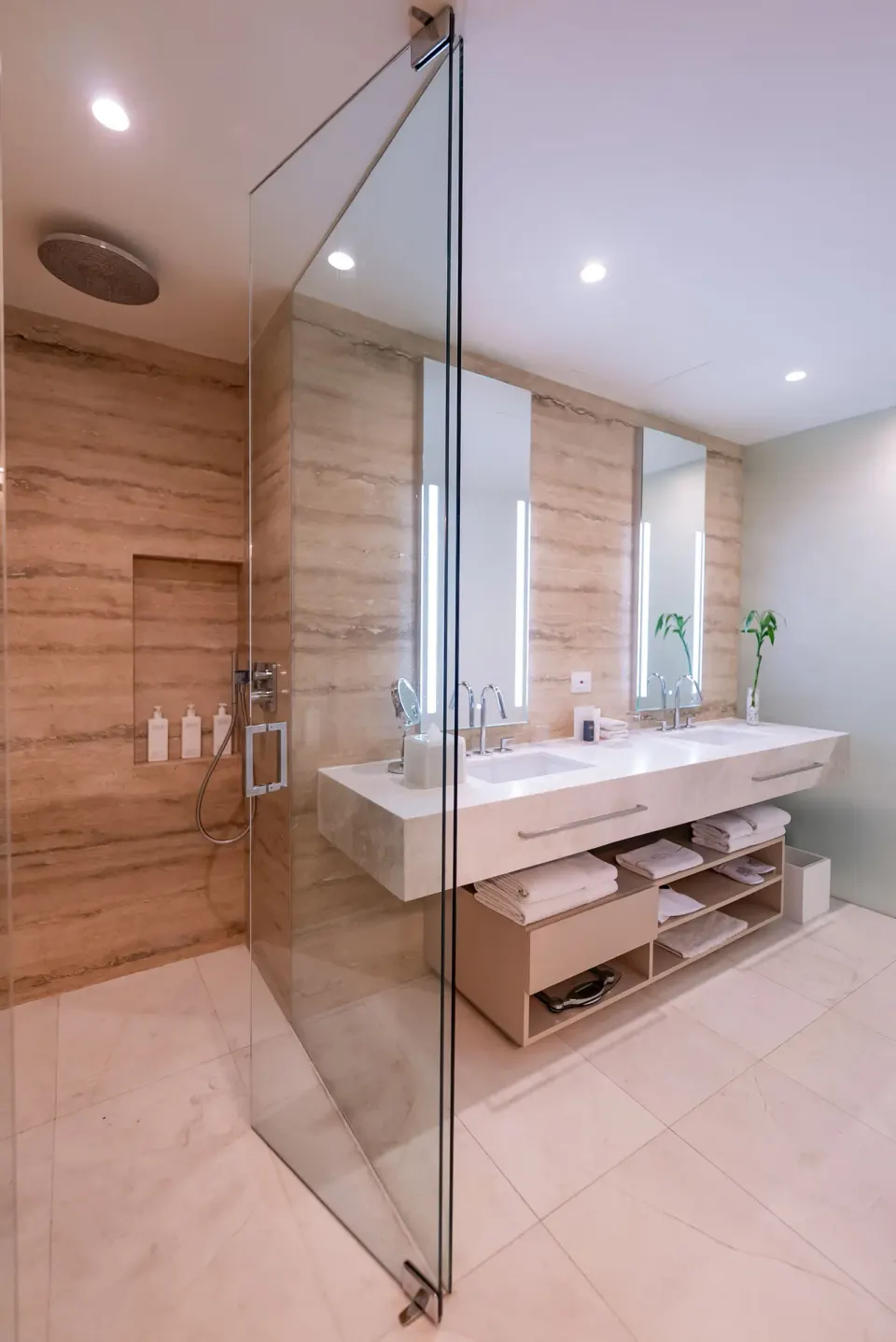 Superior Room bathroom with glass shower, double vanity and open towel shelves at SLS Cancun.