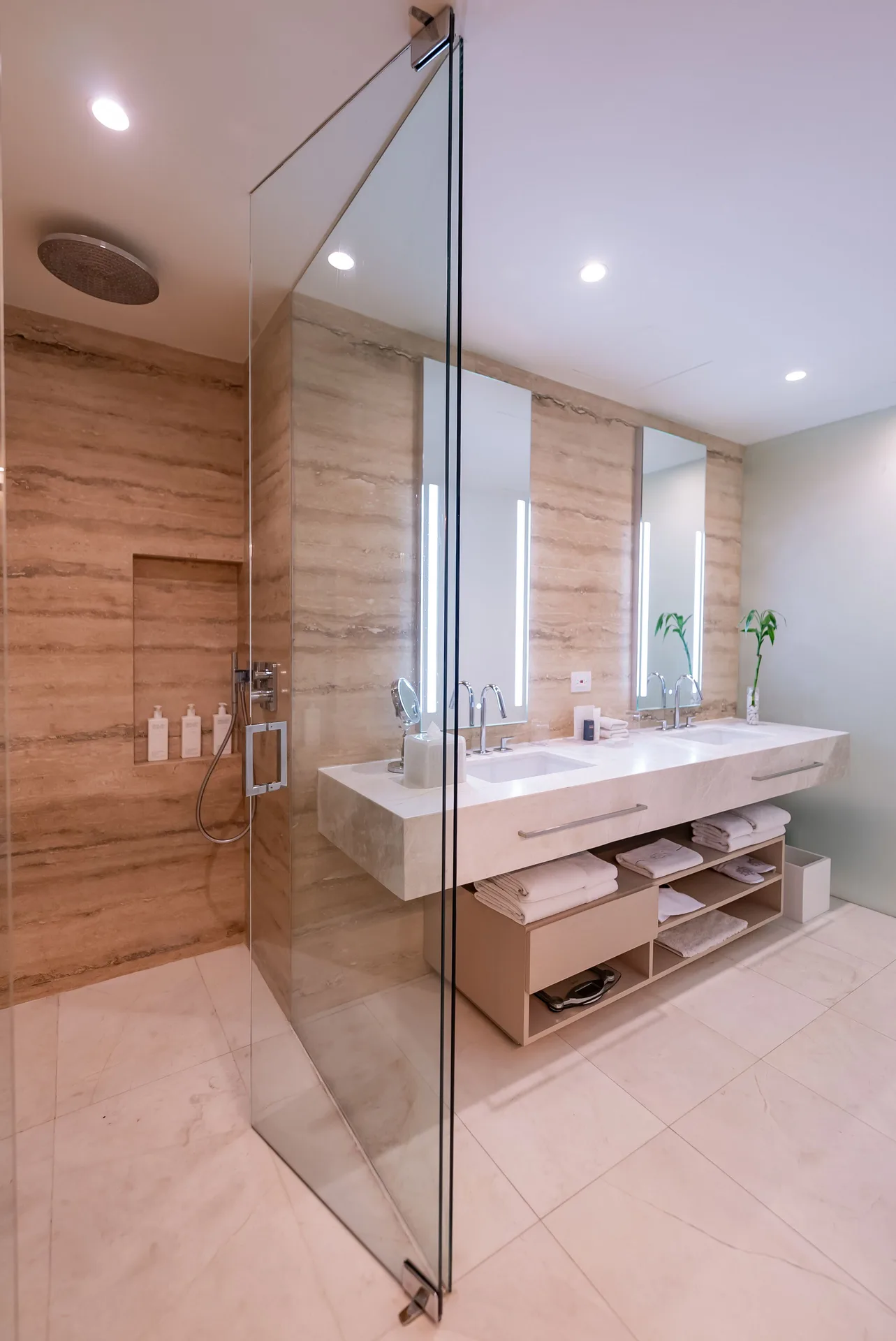 Superior Room bathroom with glass shower, double vanity and open towel shelves at SLS Cancun.