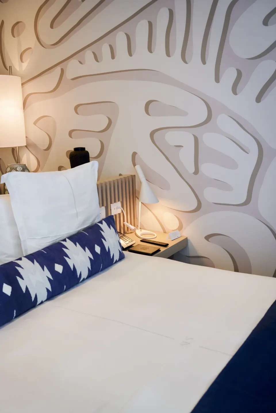 Superior Room king bed with patterned wall, bedside lamp, and nightstand at SLS Cancun.