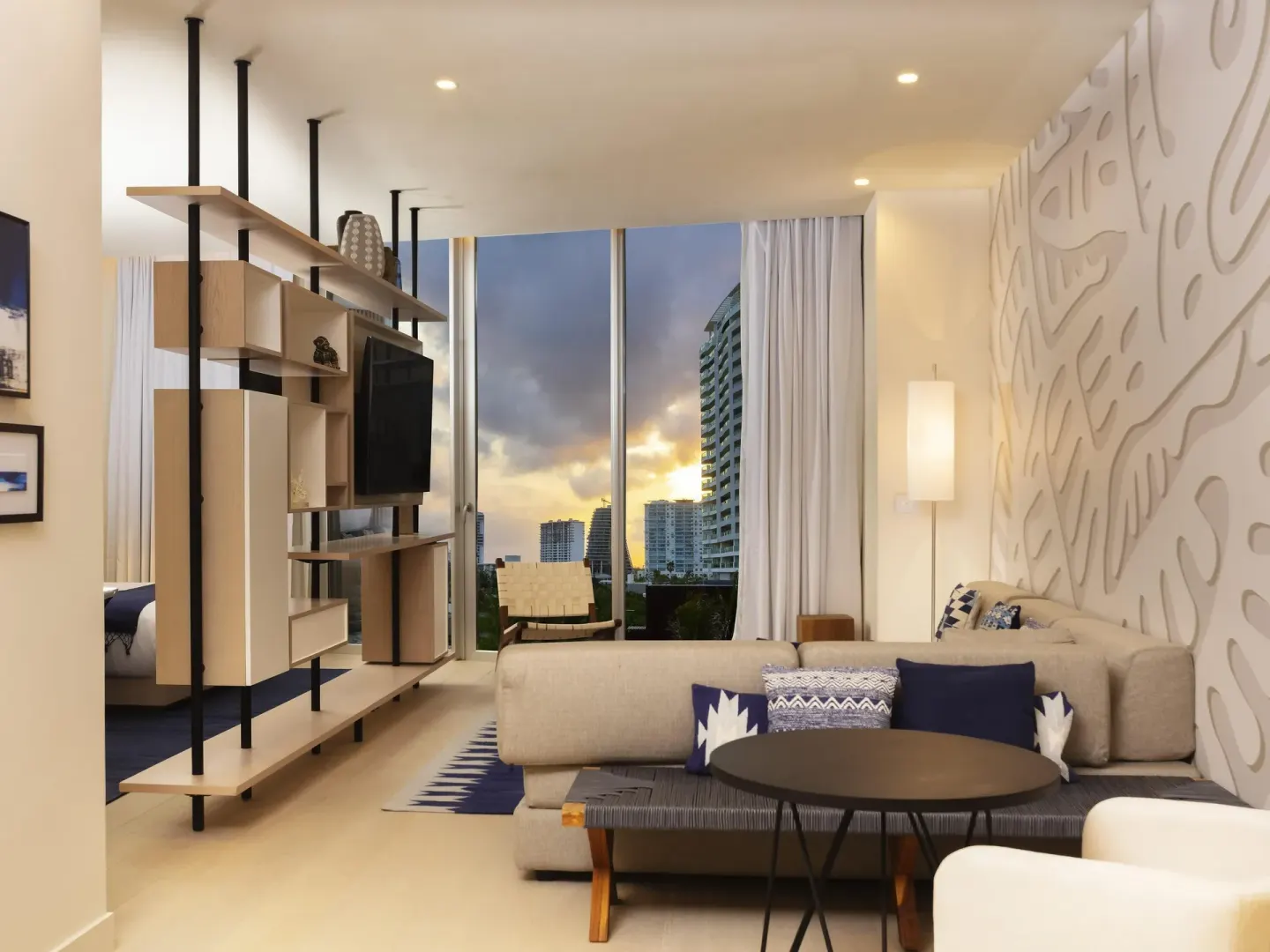Superior Room sitting area with sectional sofa, TV shelving and city-facing windows at SLS Cancun.