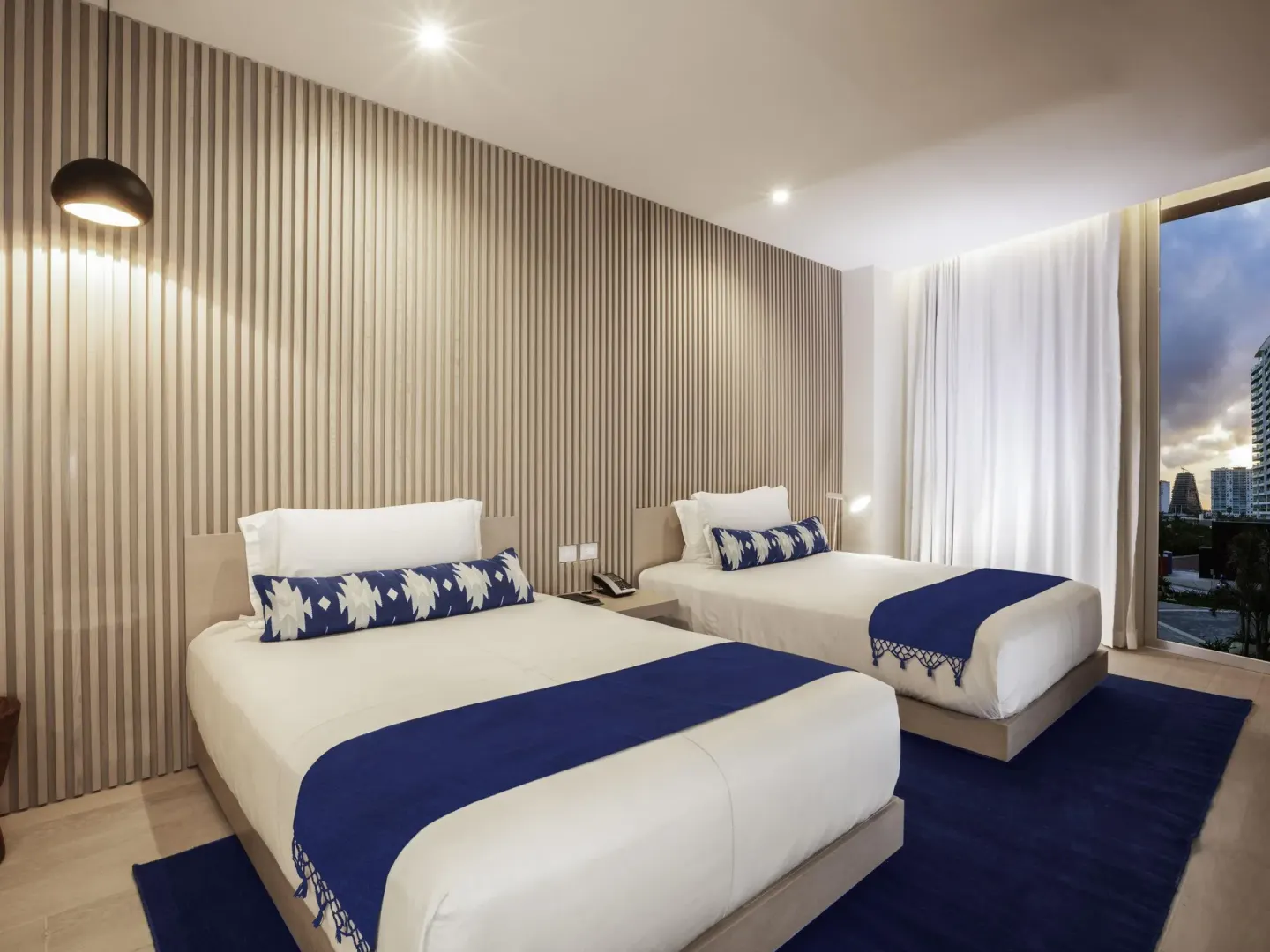 Superior Room with two beds, blue accents and floor-to-ceiling window at SLS Cancun.