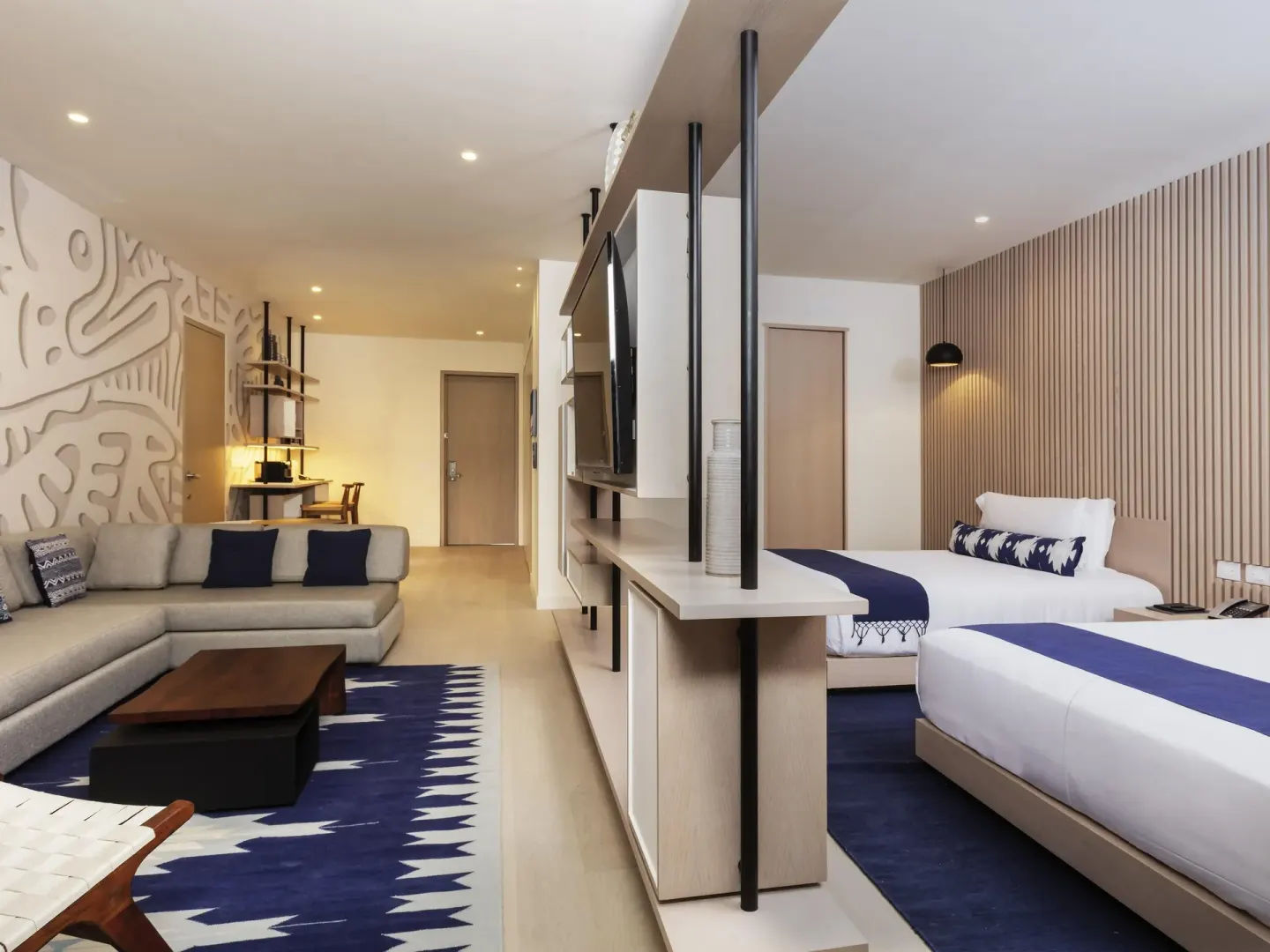 Superior Room with two beds, sofa seating, TV shelving, and blue rug at SLS Cancun.