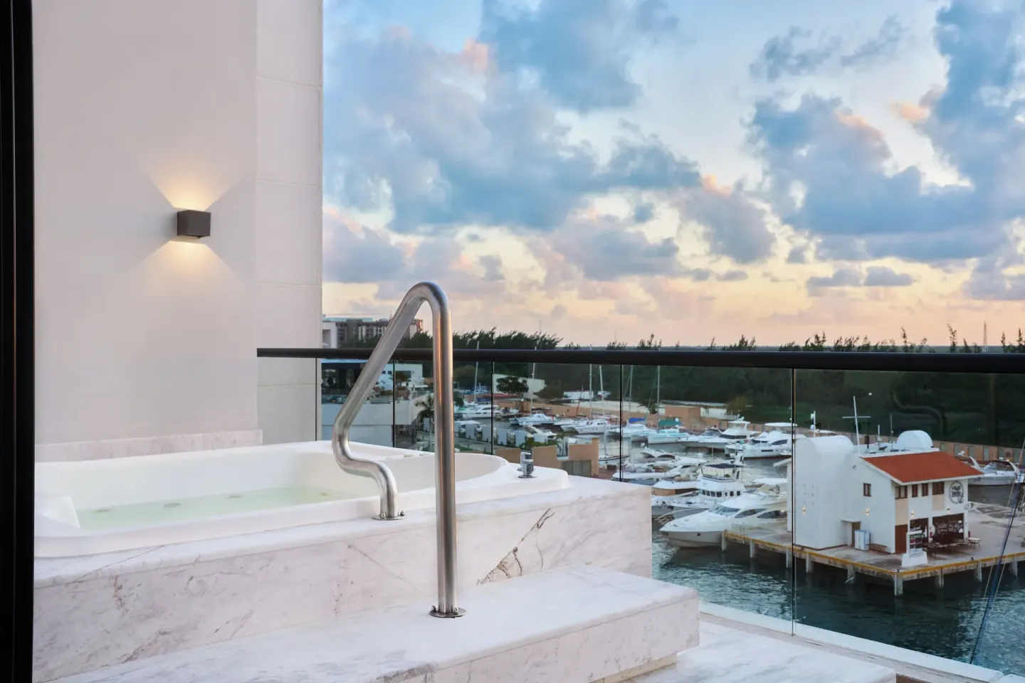 Balcony soaking tub overlooking a marina at sunset at SLS Playa Mujeres.