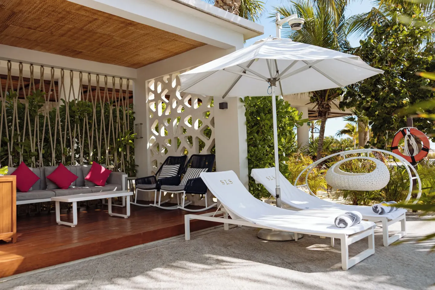 Shaded cabana terrace with loungers and cushioned seating at SLS Playa Mujeres.