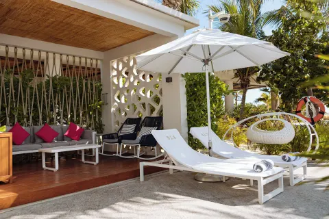 Shaded cabana terrace with loungers and cushioned seating at SLS Playa Mujeres.