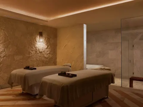 Spa treatment room with two massage tables and marble walls at SLS Playa Mujeres.