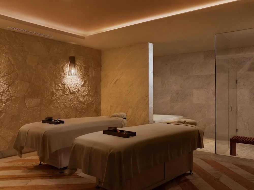 Spa treatment room with two massage tables and marble walls at SLS Playa Mujeres.