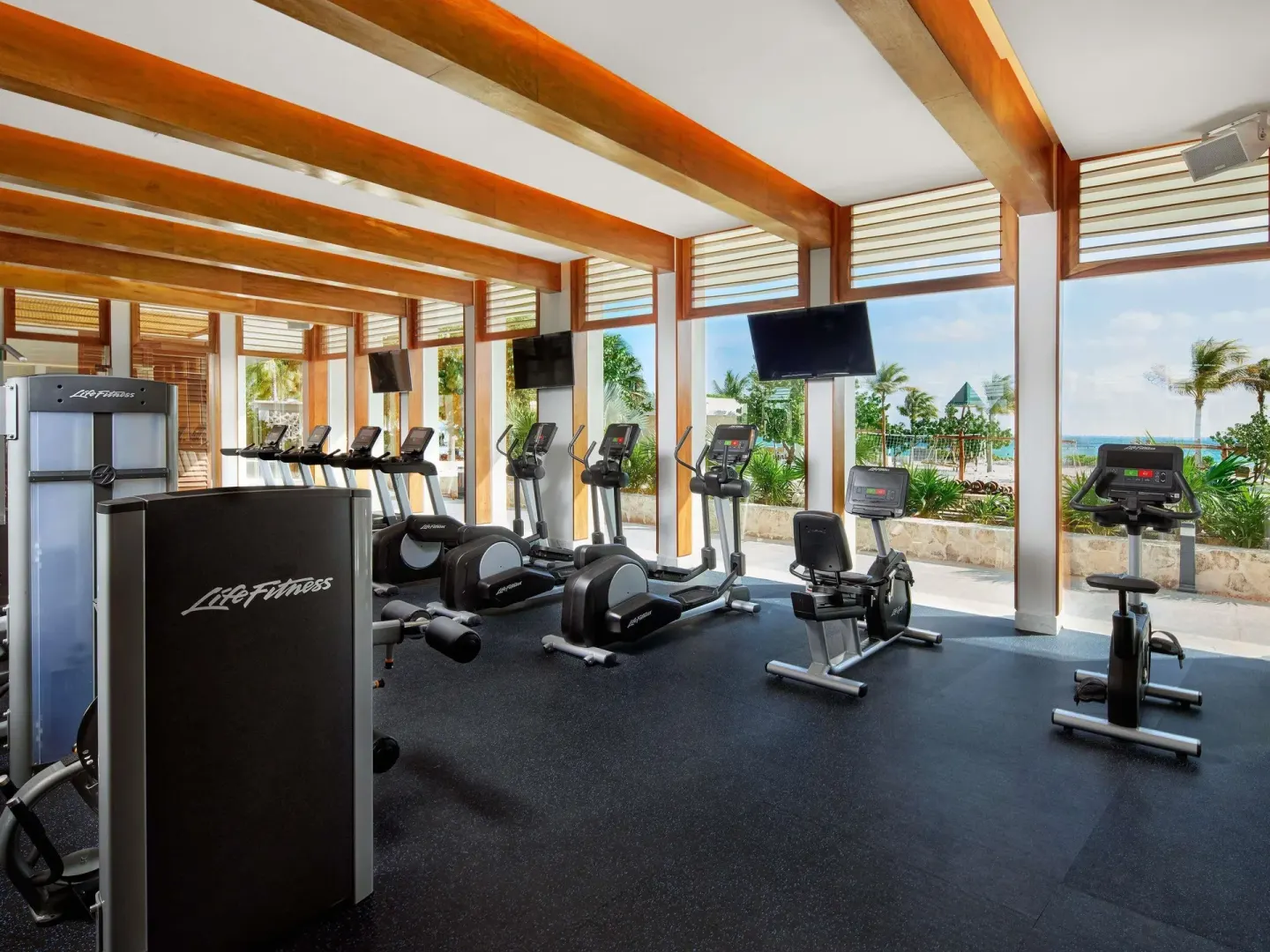 Fitness center with cardio machines and ocean-facing windows at SLS Playa Mujeres.