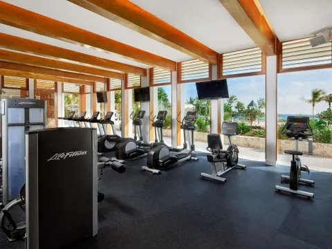 Fitness center with cardio machines and ocean-facing windows at SLS Playa Mujeres.