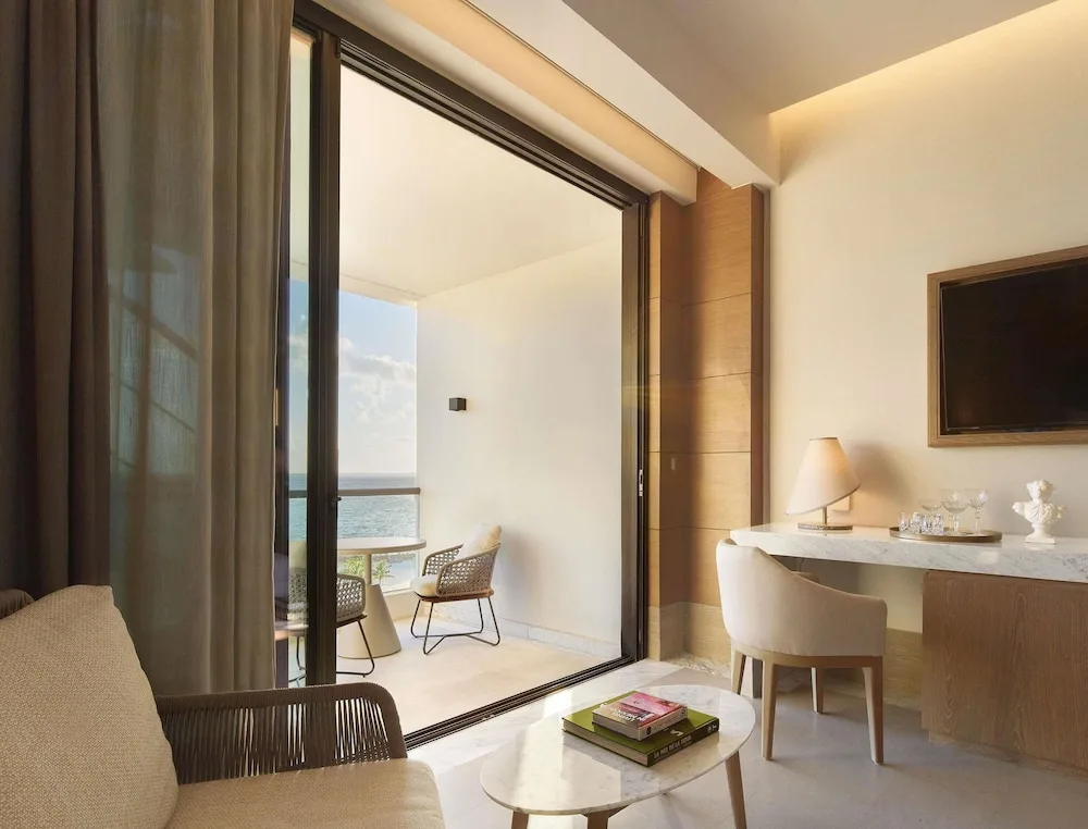 Guest room sitting area with balcony and sea view at SLS Playa Mujeres.