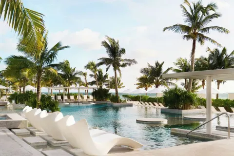 Pool loungers, palms and ocean views at SLS Playa Mujeres.