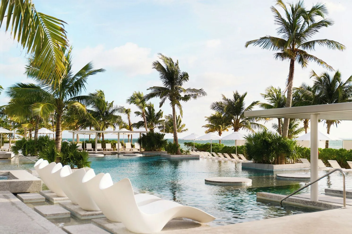 Pool loungers, palms and ocean views at SLS Playa Mujeres.