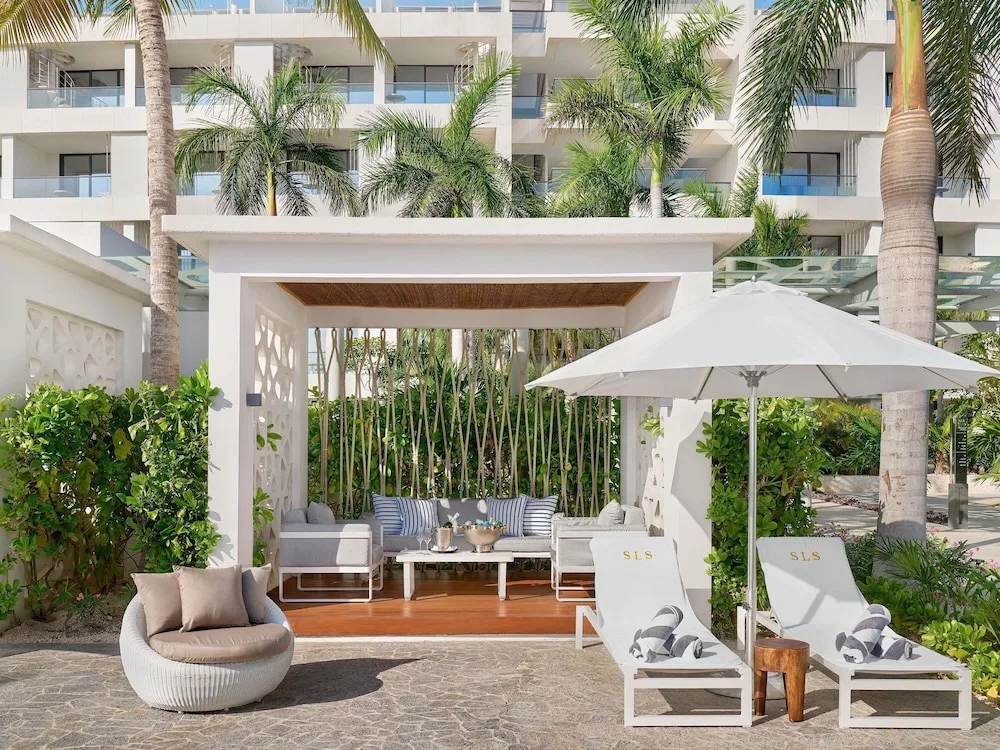 Private cabana with loungers, palms and resort balconies at SLS Playa Mujeres.