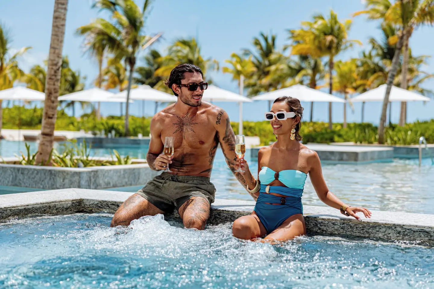 Guests with drinks in a poolside hot tub at SLS Playa Mujeres.