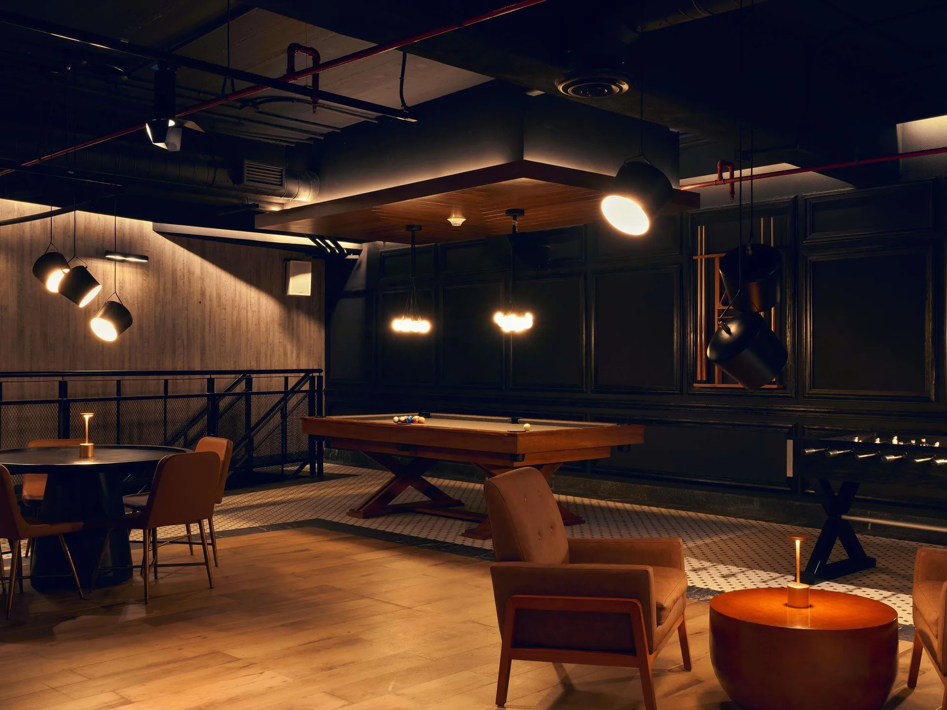 Dim lounge with billiards table, seating, and warm lighting at SLS Playa Mujeres.