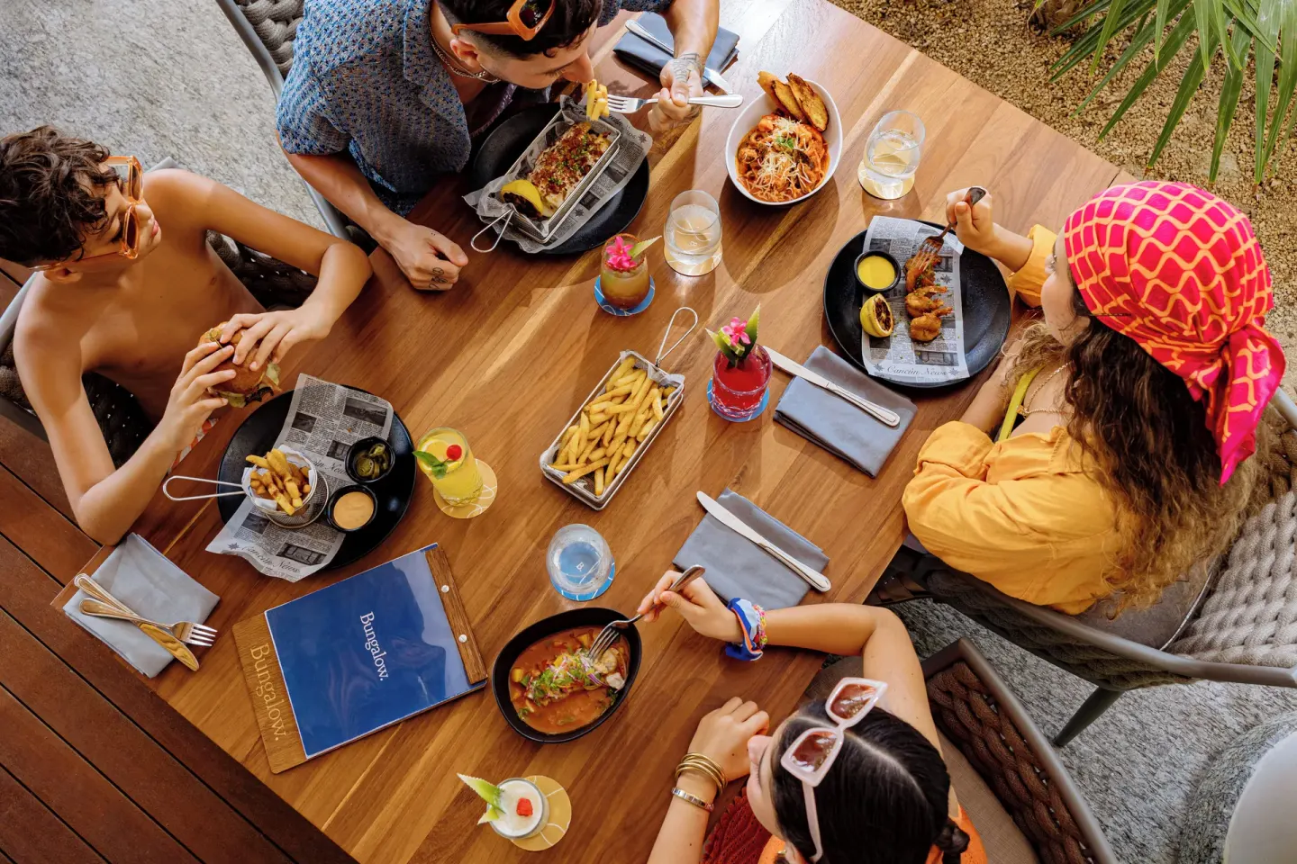 Guests sharing casual food and colorful drinks at Bungalow at SLS Playa Mujeres.