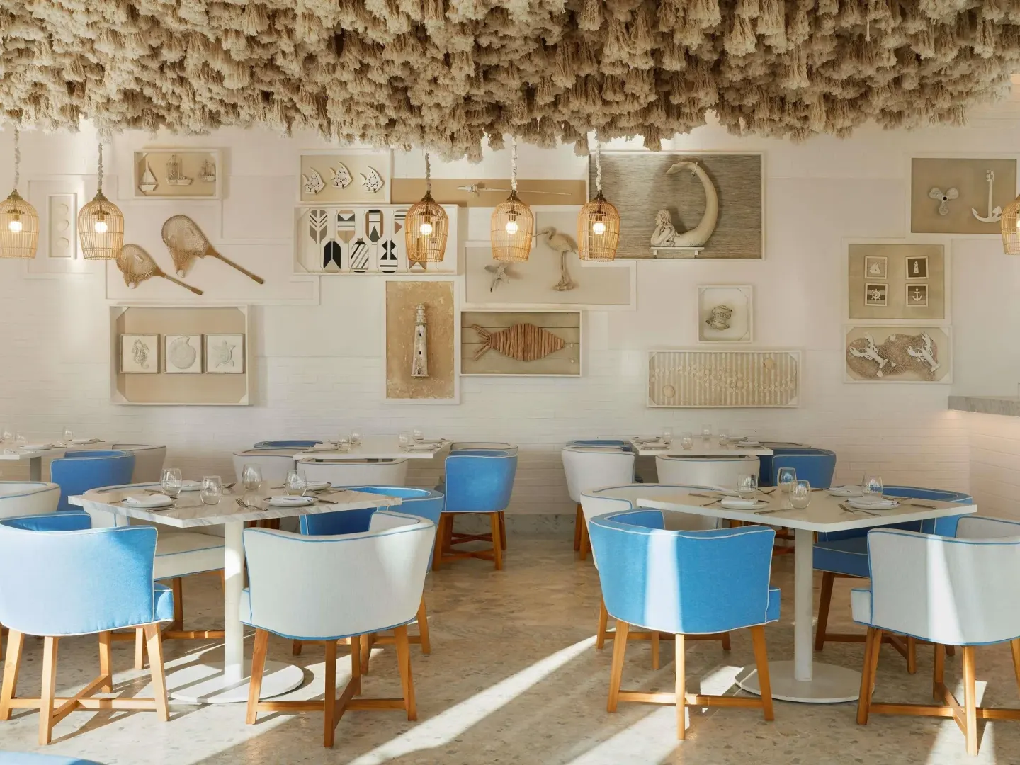 Coastal-themed dining room with blue chairs and wall art at SLS Playa Mujeres.
