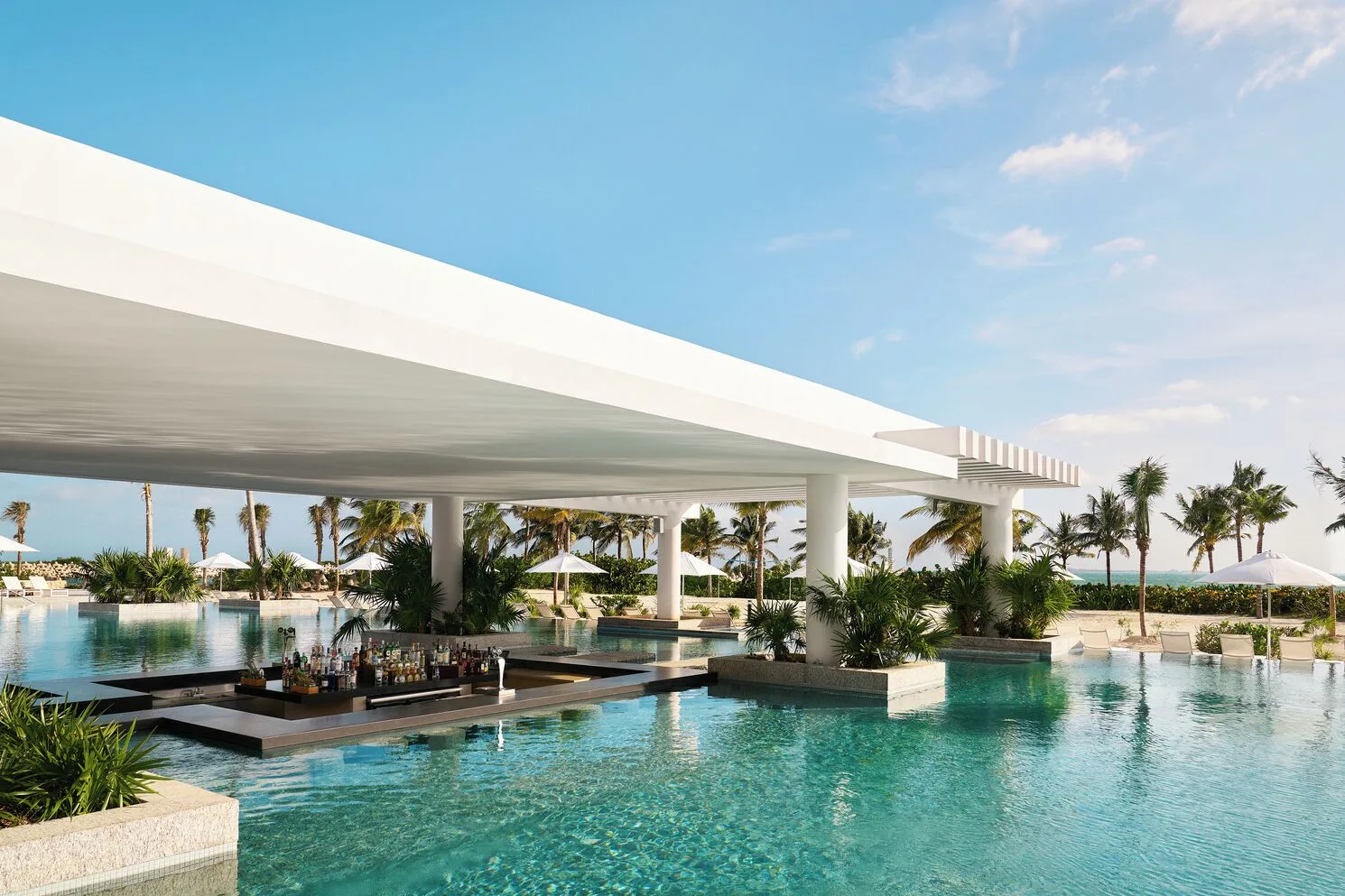 Pool bar set within a large swimming pool and white pavilion at SLS Playa Mujeres.
