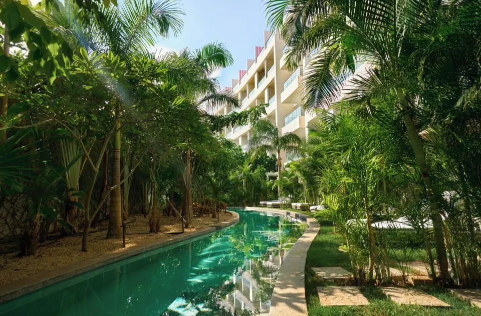 Tropical swim-out waterway beside guest room balconies at SLS Playa Mujeres.