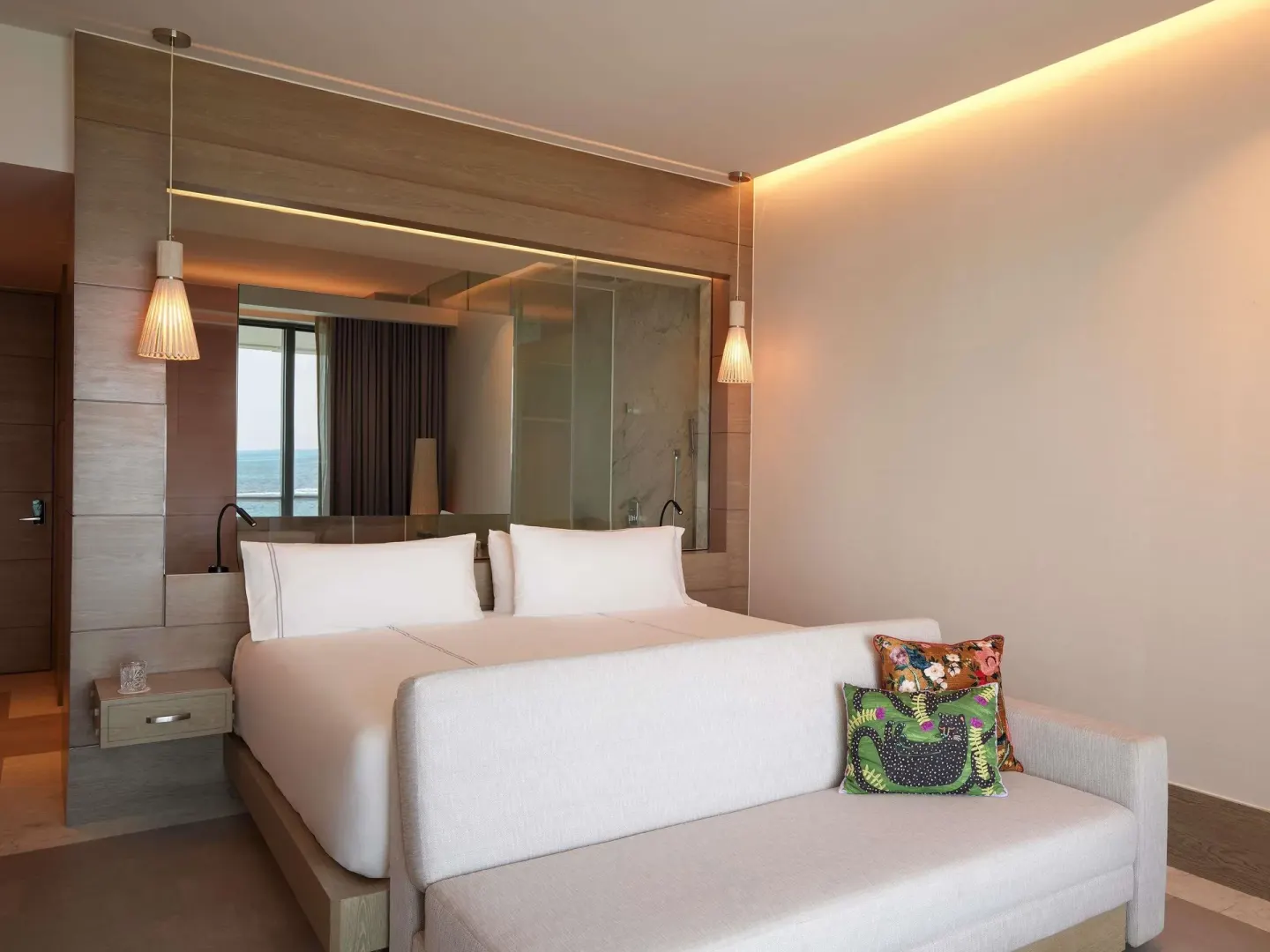 Delight guest room king bed, sofa, and window view at SLS Playa Mujeres.