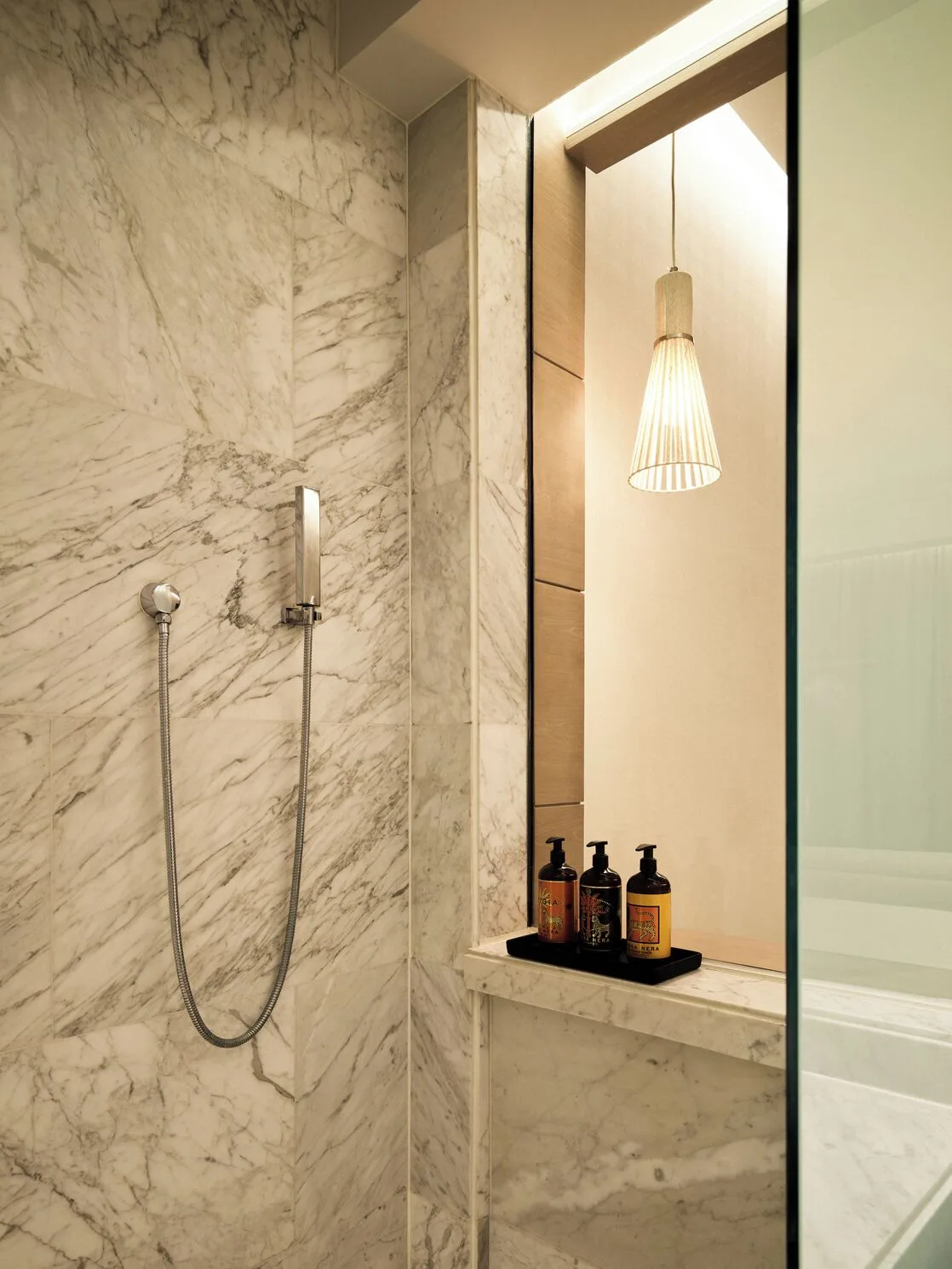 Delight guest room marble shower with handheld fixture at SLS Playa Mujeres.