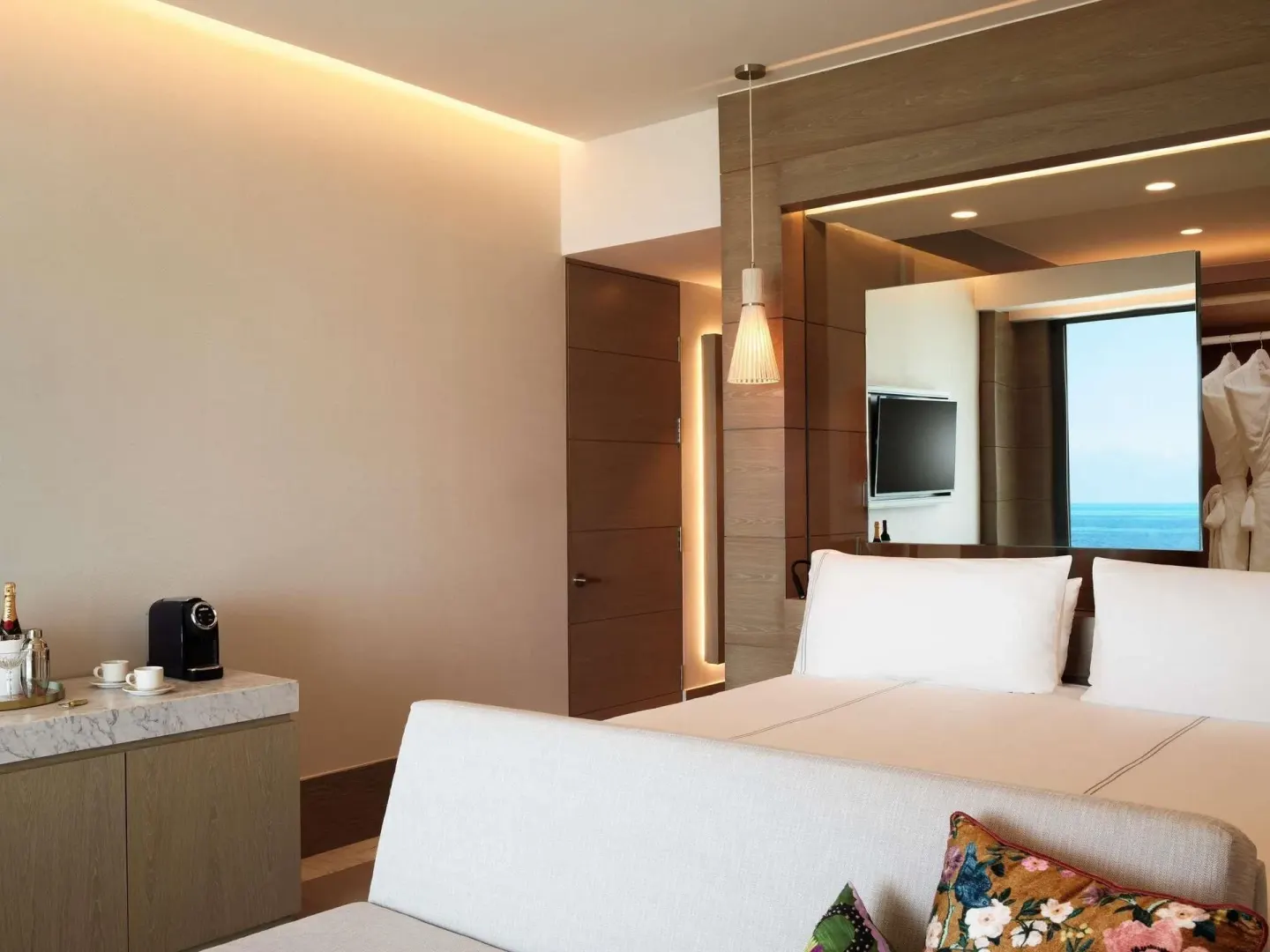 Euphoria Suite bedroom with king bed, sofa, minibar, and ocean glimpse at SLS Playa Mujeres.