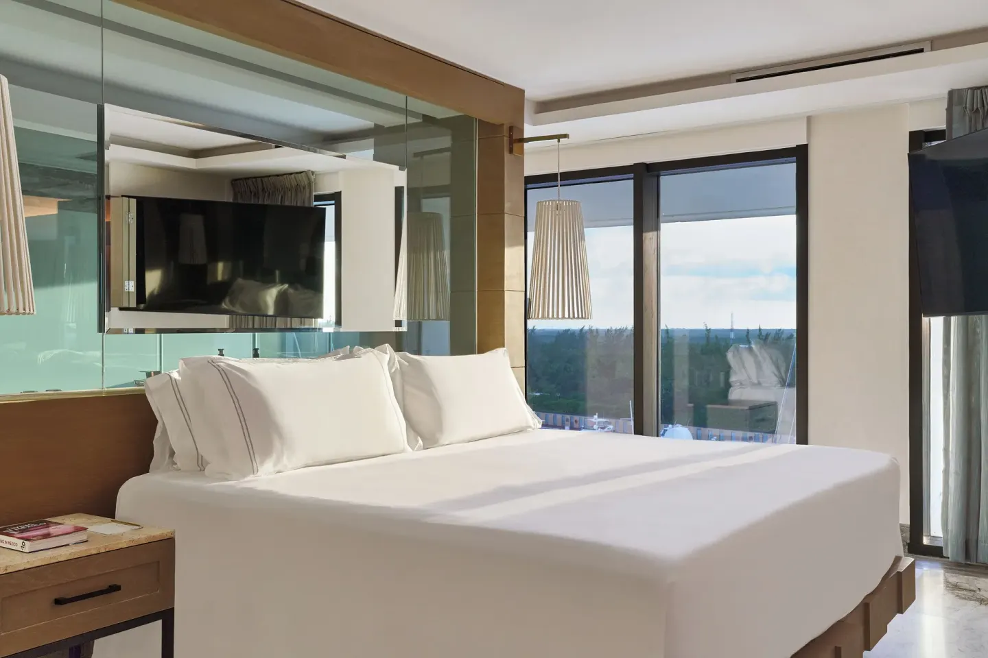 Bedroom with king bed, TV, and ocean-facing windows in a Luxuriate Two Bedroom Suite at SLS Playa Mujeres.