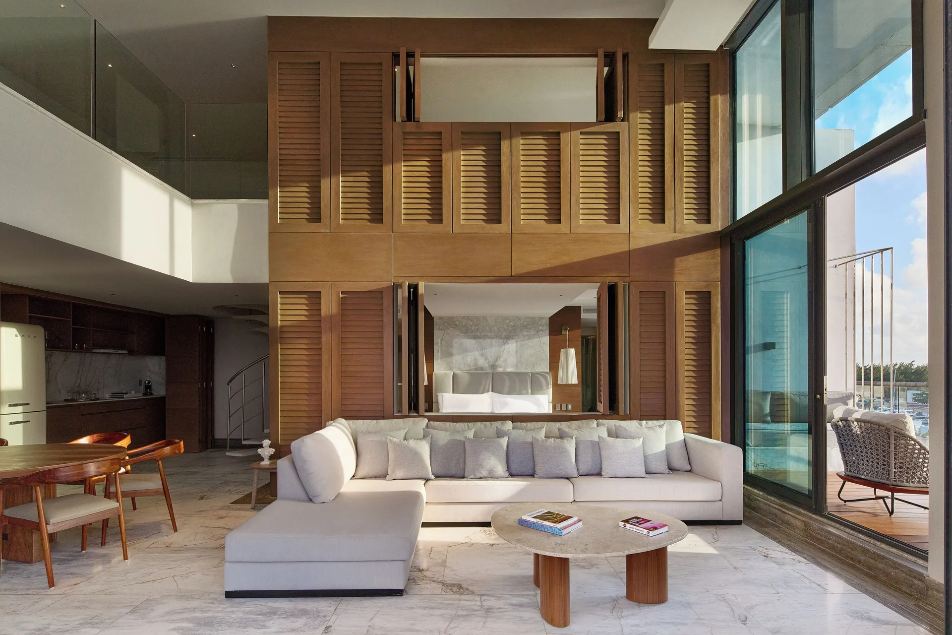Two-level living room with sofa, dining area, kitchen, and balcony in a suite at SLS Playa Mujeres.