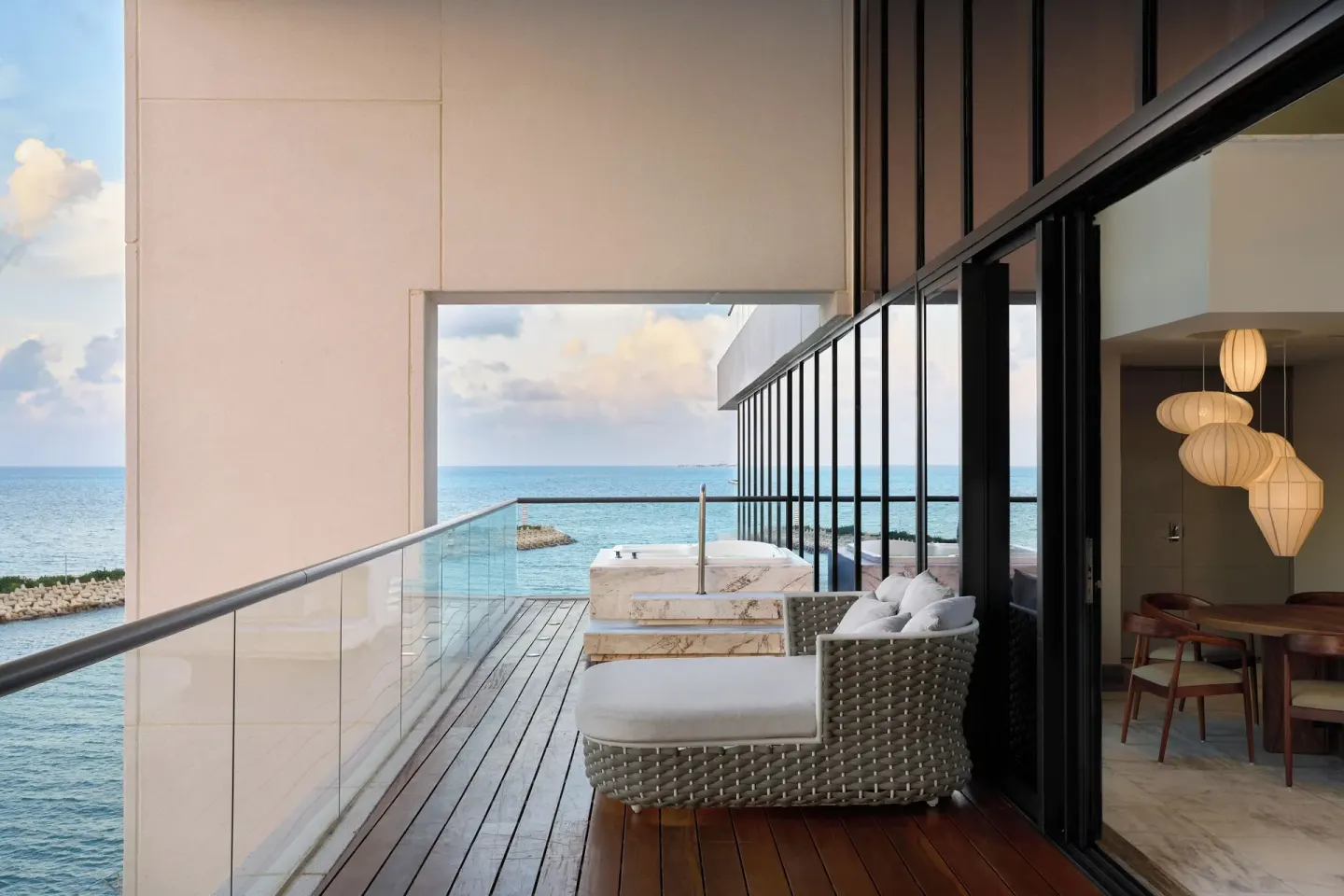 Oceanfront balcony with daybed and plunge tub outside a suite at SLS Playa Mujeres.