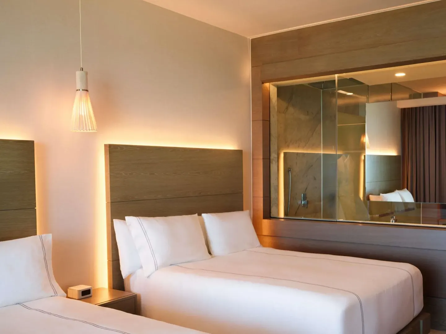 SLS Playa Mujeres guest room with two beds and a glass-walled shower at SLS Playa Mujeres.