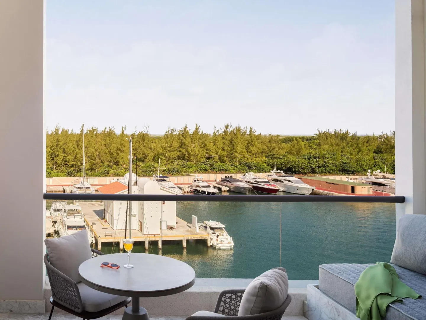 SLS Playa Mujeres balcony at SLS Playa Mujeres overlooking a marina with lounge seating and a table.