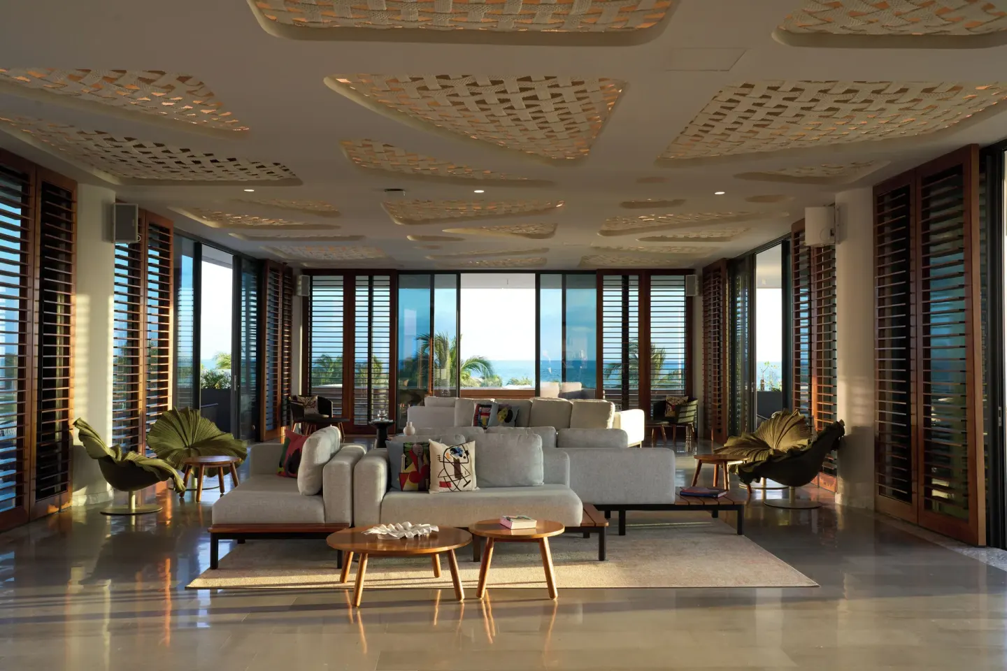 SLS Playa Mujeres living room at SLS Playa Mujeres with sofas, wood shutters, and ocean-facing windows.