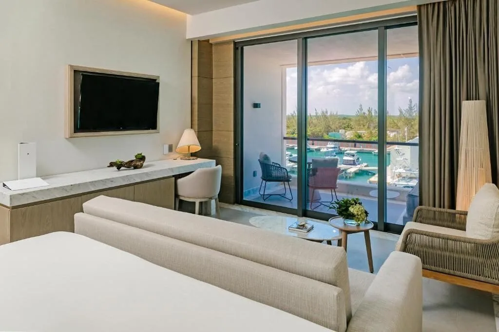 SLS Playa Mujeres king bed room at SLS Playa Mujeres with desk, seating, balcony, and marina view.