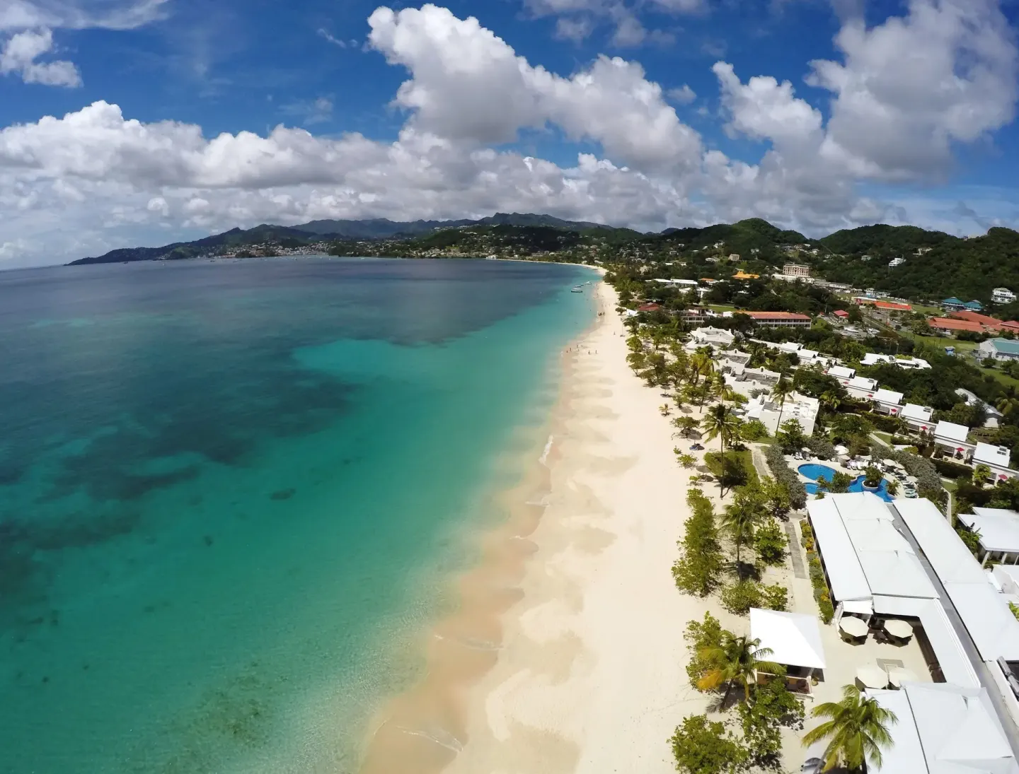 Aerial view of the beach, turquoise water and resort buildings at Spice Island Beach Resort.