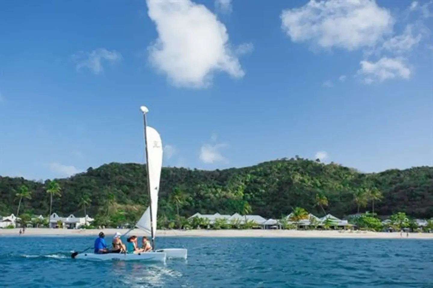 Guests sail a small catamaran off the beach at Spice Island Beach Resort.