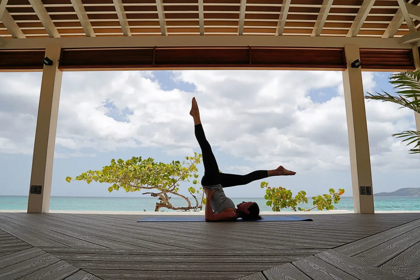 Guest practicing yoga in an open beach pavilion at Spice Island Beach Resort.