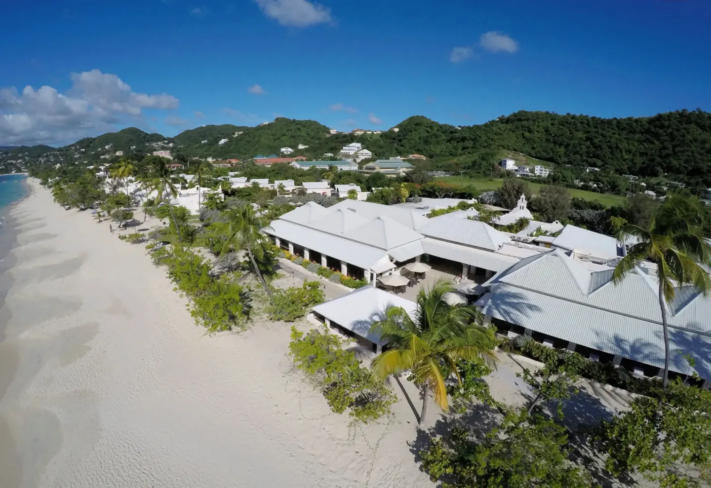 Aerial view of beachfront buildings and sand at Spice Island Beach Resort.