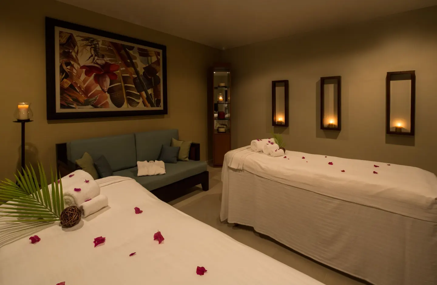 Candlelit spa room with two treatment beds and rose petals at Spice Island Beach Resort.