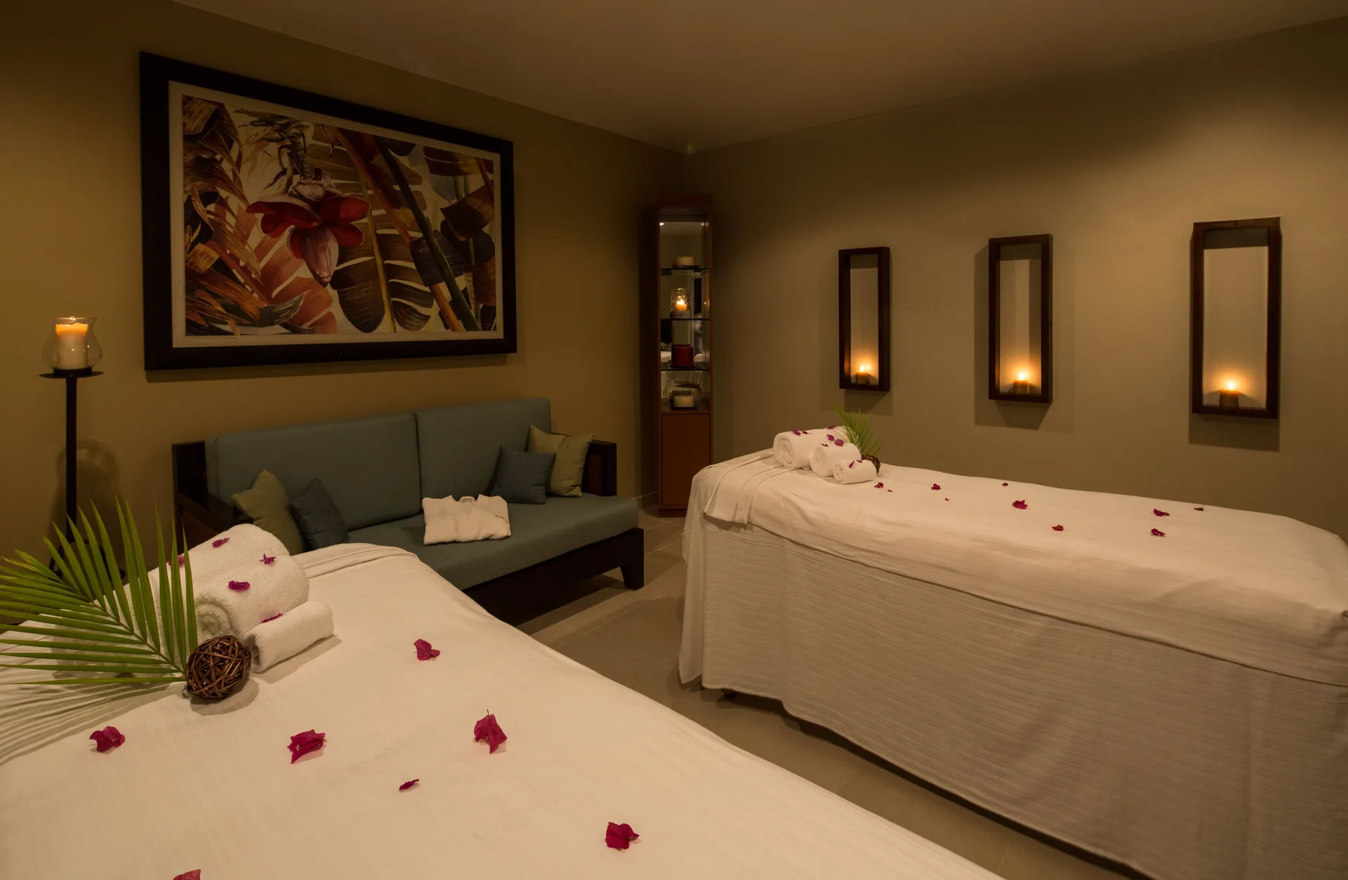 Candlelit spa room with two treatment beds and rose petals at Spice Island Beach Resort.