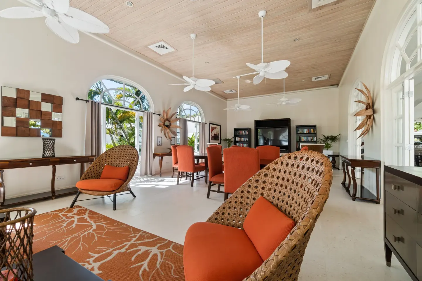 Indoor lounge with wicker chairs, orange cushions and arched windows at Spice Island Beach Resort.