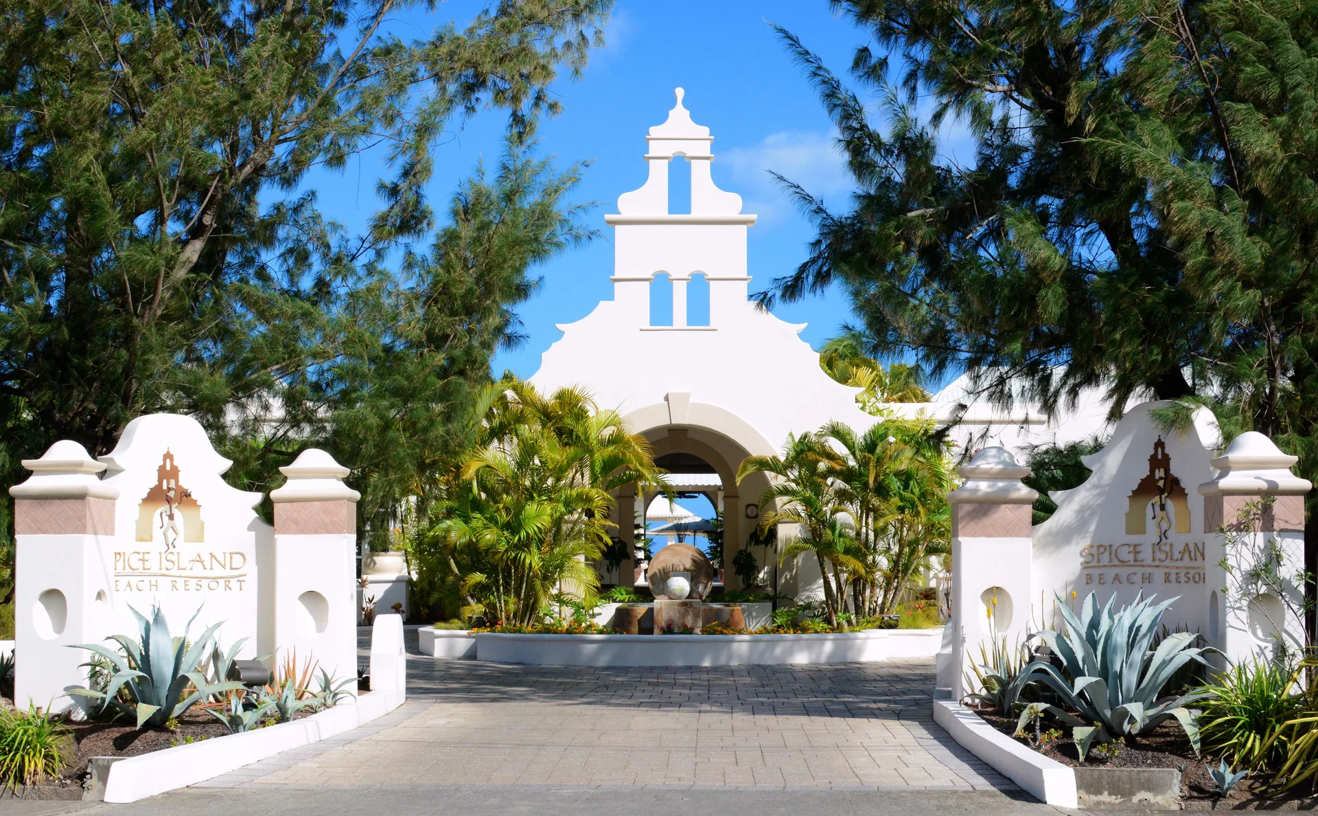 Main entrance sign and white archway at Spice Island Beach Resort.