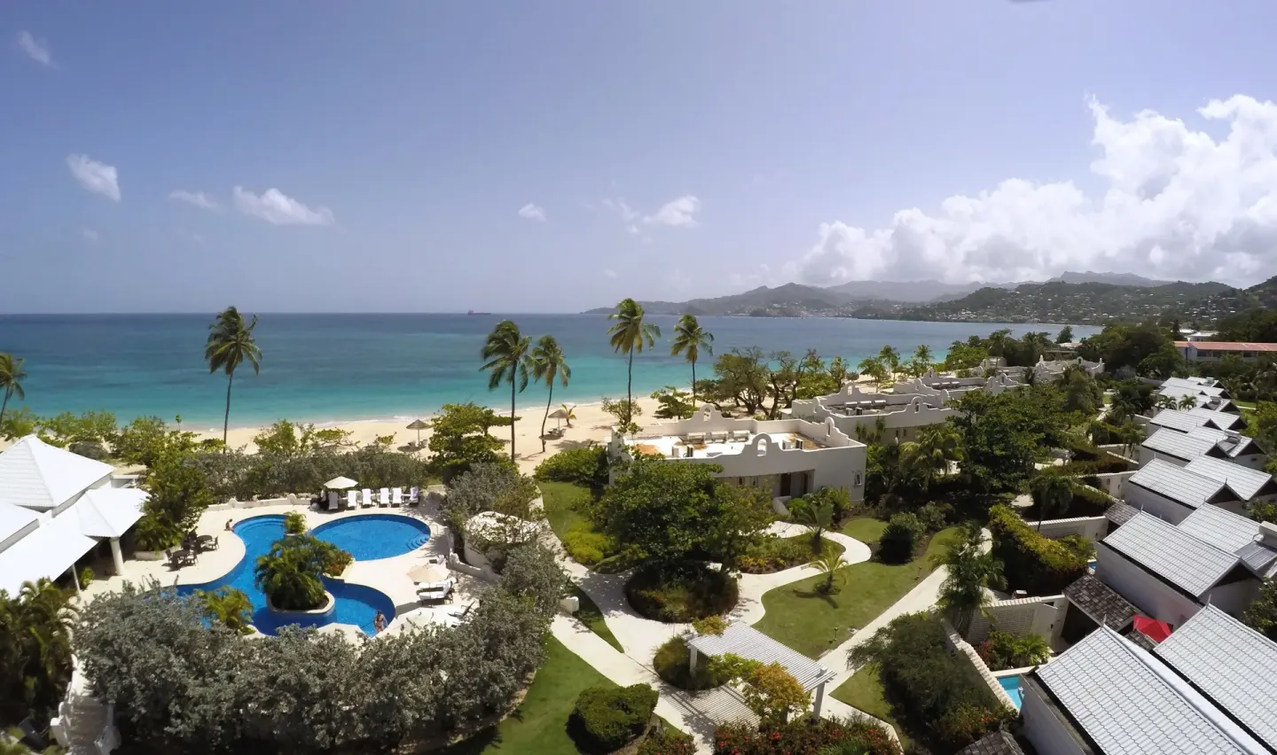 Aerial view of pool, gardens, beach, and sea at Spice Island Beach Resort.