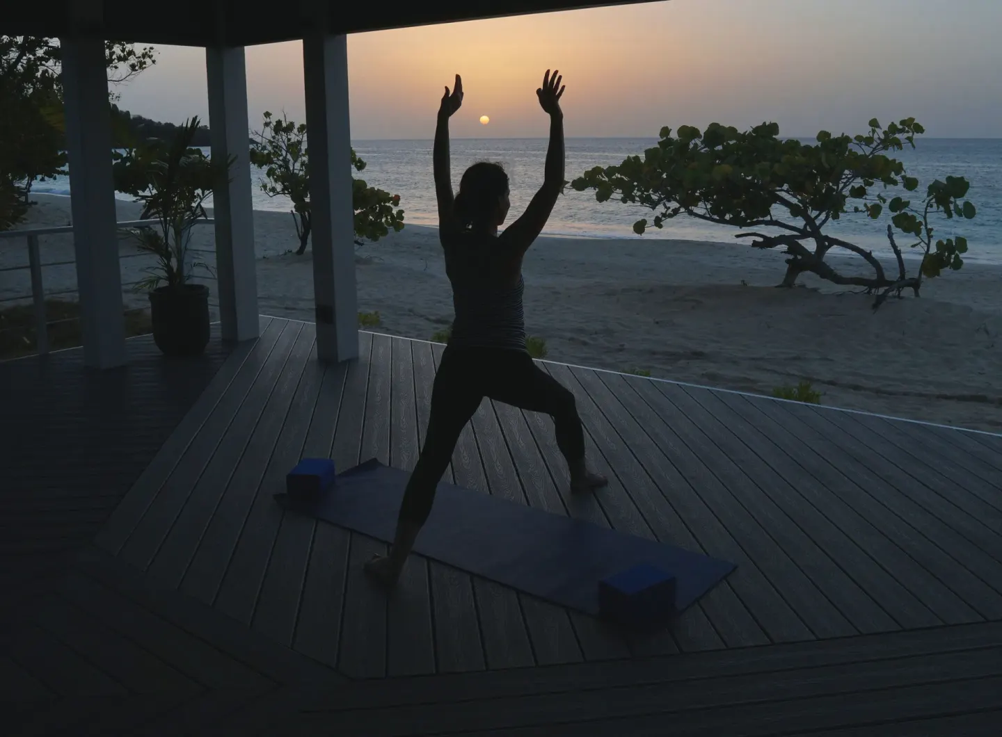Silhouetted yoga pose at sunset by the beach at Spice Island Beach Resort.