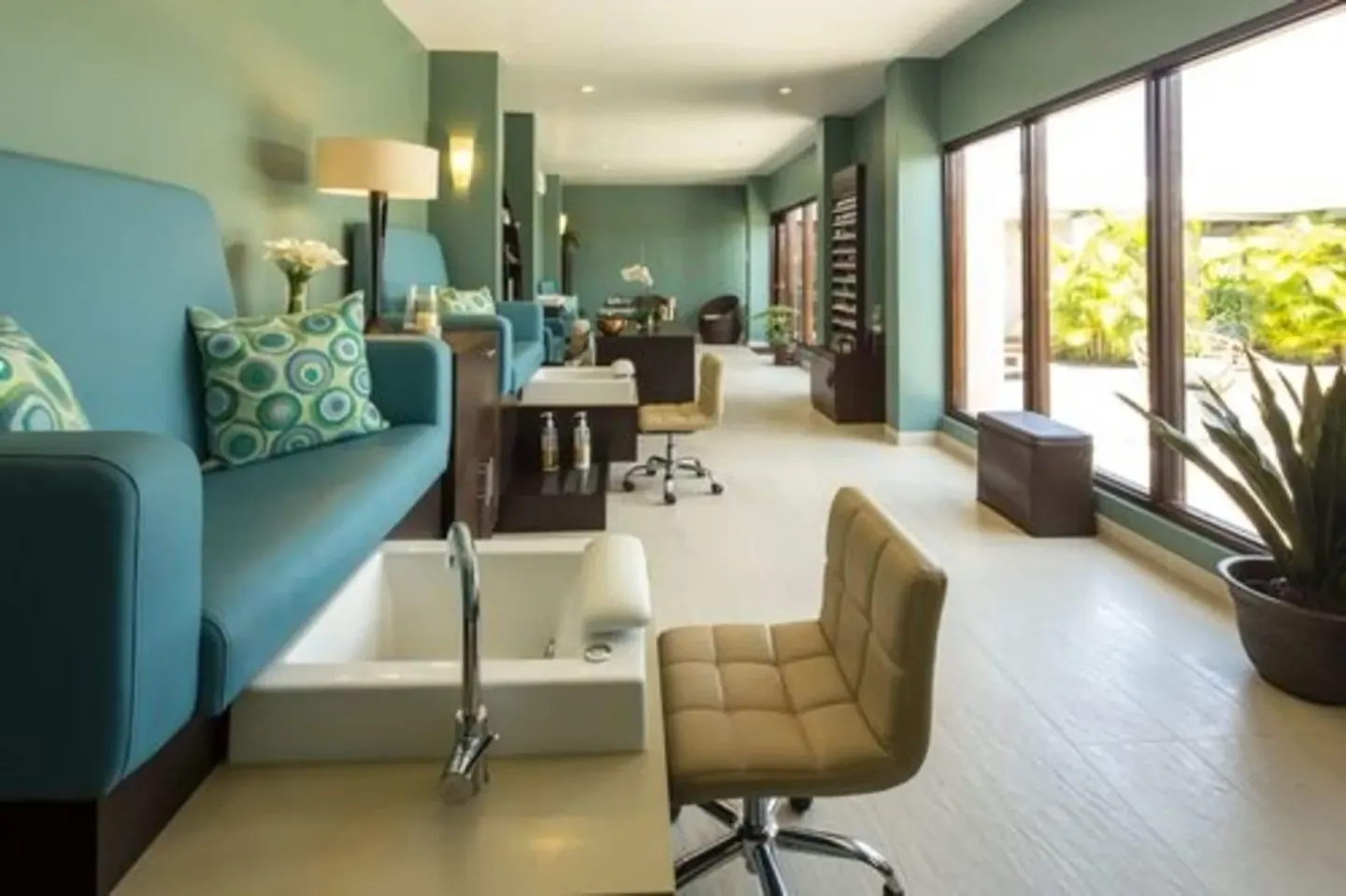 Long spa salon with pedicure chair, blue benches, and garden-facing windows at Spice Island Beach Resort.