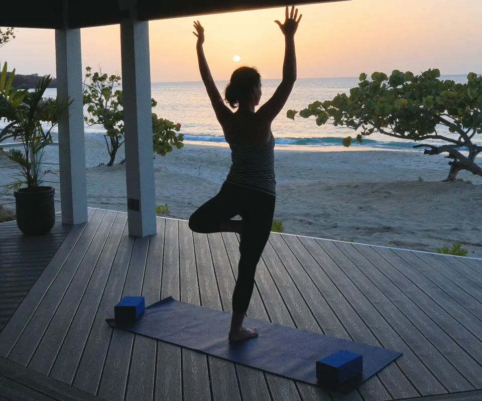 Sunset yoga silhouette on a beachfront deck at Spice Island Beach Resort.