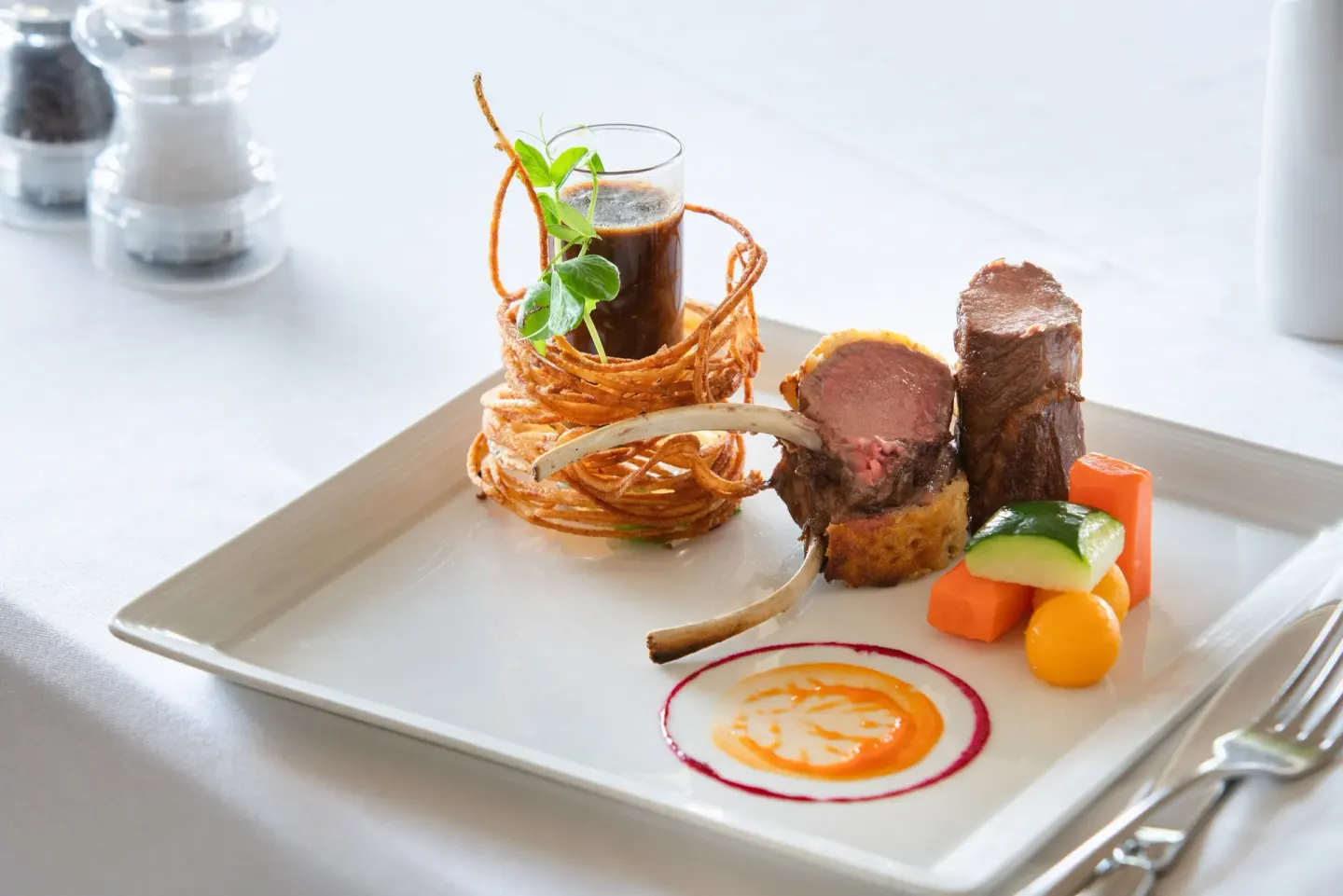 Plated lamb dish with vegetables at Spice Island Beach Resort.