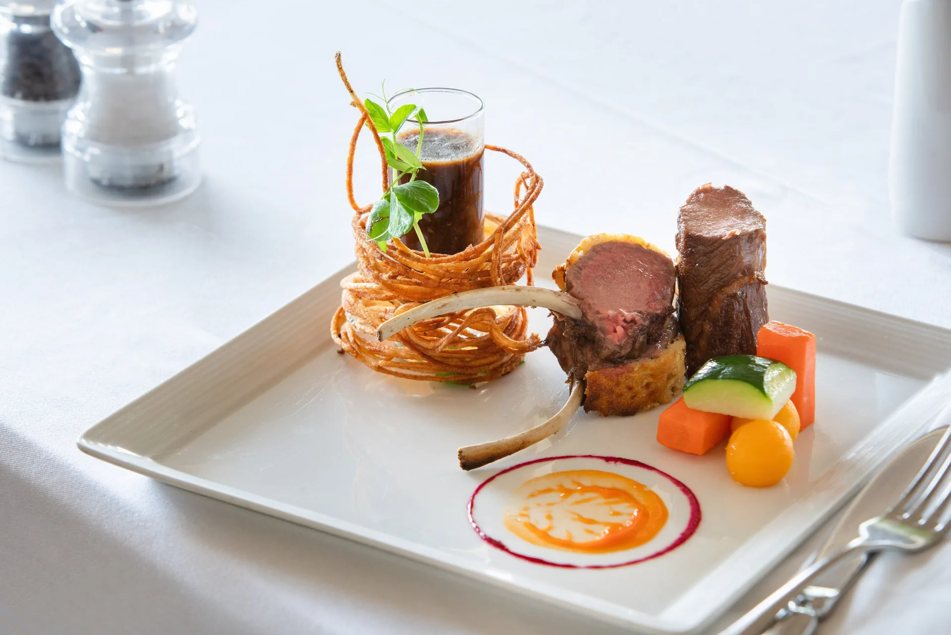 Plated lamb dish with vegetables at Spice Island Beach Resort.